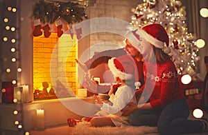 Happy family sitting by fireplace on Christmas Eve