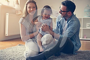 Happy family sitting on floor with their little baby.