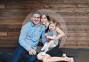 Happy family sitting on floor with their little baby