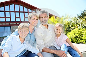 Happy family sitting in font of their home