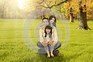 Happy family sitting on grass at autumn season