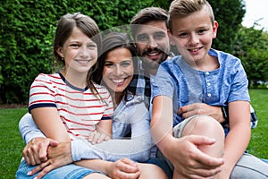 Happy family sitting on grass in park on a sunny day