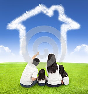 Happy family sitting on a meadow with house of clouds