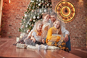 Happy family sitting near Christmas tree in cozy living room