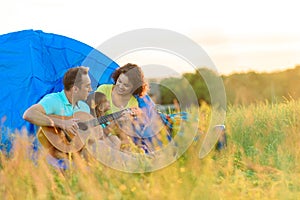 Happy family sitting near tent