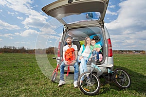 Happy family sitting in open luggage boot outside