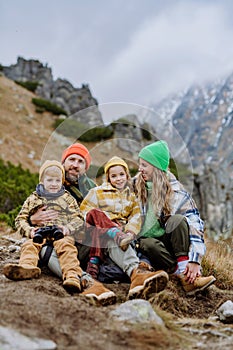 Šťastná rodina sedí a odpočíva pri spoločnej turistike v jesenných horách.