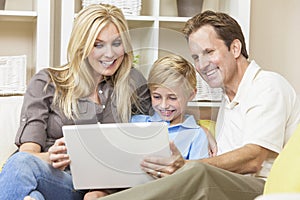 Happy Family Sitting on Sofa Using Laptop Computer