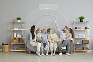 Happy family sitting together on a couch at home under a new modern air conditioner