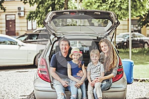 Happy family sitting in the trunk of a family car