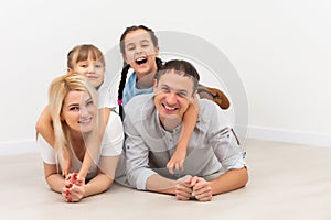 Happy family sitting on wooden floor. Father, mother and child having fun together. Moving house day, new home concept