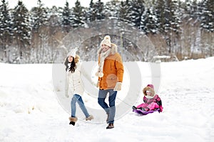 Happy family with sled walking in winter forest