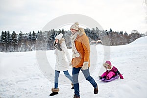 Happy family with sled walking in winter outdoors