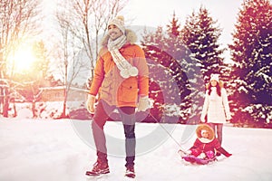 Happy family with sled walking in winter outdoors