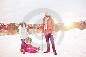 Happy family with sled walking in winter outdoors