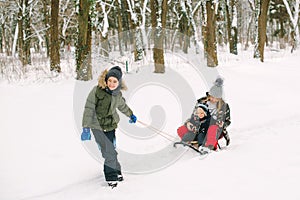 Happy family with sled in winter having fun together. Family driving sled under winter snow. Christmas vacation