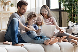 Happy family with small children watching video on laptop