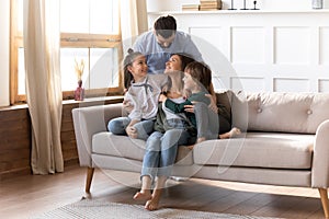 Happy family with small kids relax on couch cuddle together