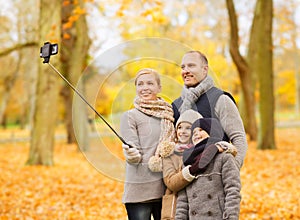 Happy family with smartphone and monopod in park