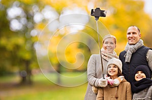 Happy family with smartphone and monopod in park