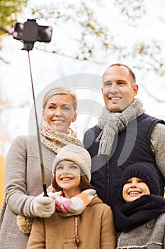 Happy family with smartphone and monopod in park