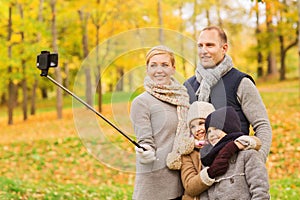 Happy family with smartphone and monopod in park