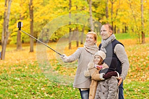 Happy family with smartphone and monopod in park