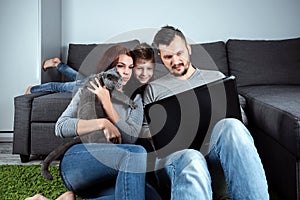 A happy family, with smiles watching something in a laptop. The concept of joint pastime, vacation, joint rest, family