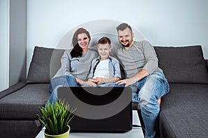 A happy family, with smiles watching something in a laptop. The concept of joint pastime, vacation, joint rest, family