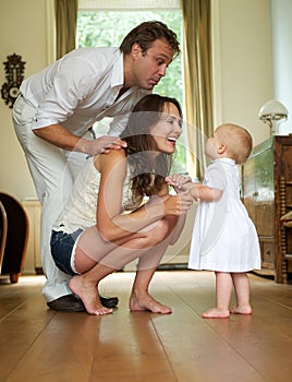 Happy family smiling at baby standing at home