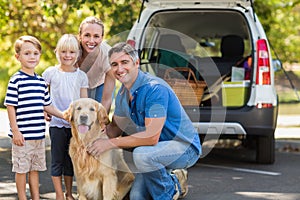 Happy family smiling at the camera with their dog