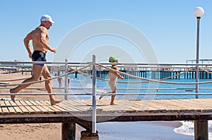 Happy family. Smiling grandfather and grandson playing at the sea. Running to the wave. Positive human emotions, feelings,