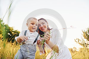 Happy family smiling and having fun. Young mother with her little son is outdoors in the agricultural field. Beautiful sunshine