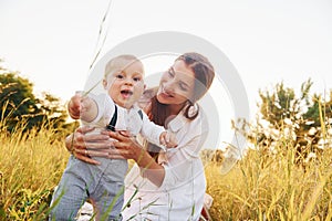 Happy family smiling and having fun. Young mother with her little son is outdoors in the agricultural field. Beautiful sunshine