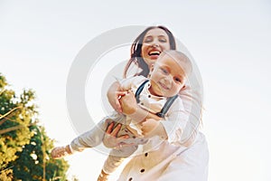 Happy family smiling and having fun. Young mother with her little son is outdoors in the agricultural field. Beautiful sunshine