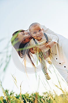 Happy family smiling and having fun. Young mother with her little son is outdoors in the agricultural field. Beautiful sunshine