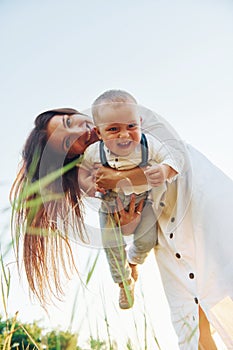 Happy family smiling and having fun. Young mother with her little son is outdoors in the agricultural field. Beautiful sunshine