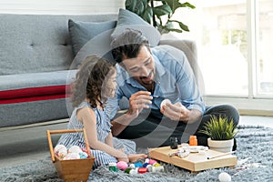 Happy family smiling. Little daughter and father painting colourful Easter eggs