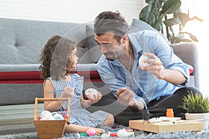 Happy family smiling. Little daughter and father painting colourful Easter eggs