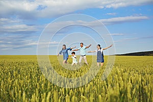 Happy family smiling running on the field in nature