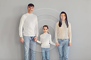 Happy family smiling while standing against gray background.