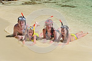 Happy family in snorkels on tropical beach photo