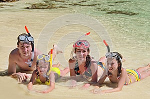 Happy family in snorkels on tropical beach photo