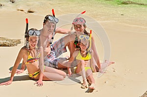 Happy family in snorkels on tropical beach on vacation