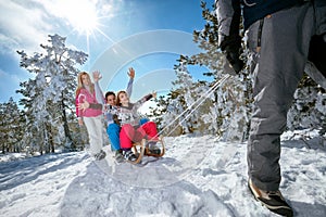 Family on snow sledding and enjoying on sunny winter day