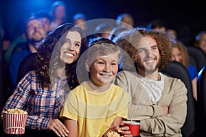 Happy family with son enjoying cartoon in cinema hall.