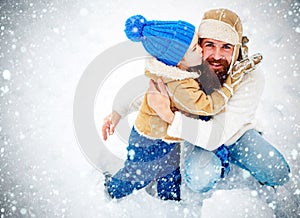 Happy family son hugs his dad on winter holiday. Merry Christmas and Happy New Year. Daddy and boy smiling and hugging.