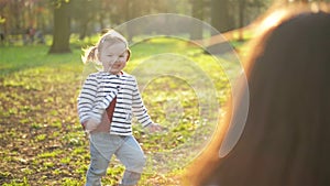 Happy Family Spending Free Time Together in the Park. Little Cute Girl with Two Ponytails is Running to Young Mother and