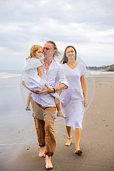 Happy family spending time at the beach. Summer holidays. Family vacation. Mother, father and daughter walking along the beach.