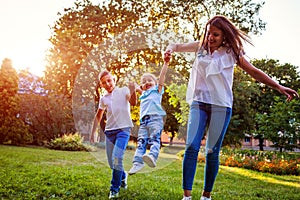 Happy family spending time outdoors playing in park. Mom having fun with two kids. Tossing girl up. Family values